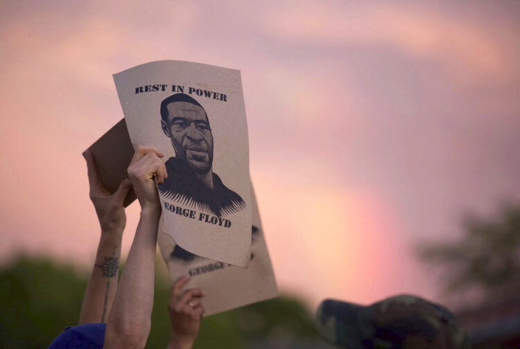A protester holds a sign with an image of George Floyd during protests Wednesday, May 27, 2020, in Minneapolis against the death of Floyd in Minneapolis police custody earlier in the week. (Christine T. Nguyen/Minnesota Public Radio via AP)